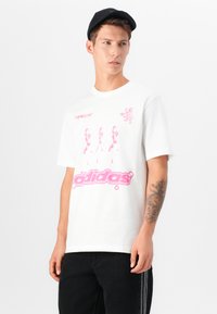 Hvit bomull t-skjorte med rosa grafisk trykk, "adidas" logo og skjermtrykt design. Korte ermer og rund hals.