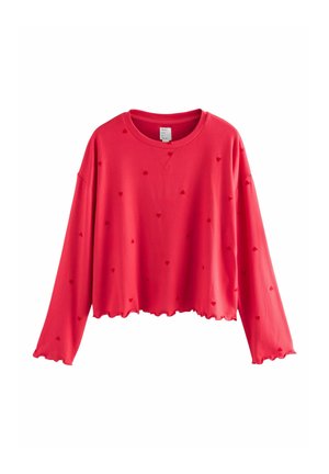 Red cropped sweatshirt with long sleeves, featuring a scalloped hem and raised heart patterns throughout the fabric. Soft texture.