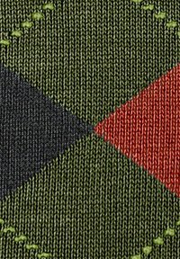 Teksturowana tkanina z geometrycznym wzorem, składająca się z zielonych, czarnych, czerwonych i pomarańczowych diamentów, przeszyta kontrastującą zieloną nicią.