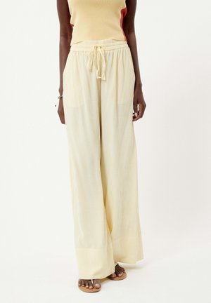 Pantalons larges rayés de couleur jaune clair. Taille élastique avec cordon de serrage, poches latérales et texture douce. Coupe décontractée et confortable.