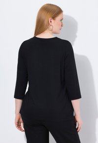 Zwarte top met driekwart mouwen, een relaxte pasvorm en een ronde halslijn. Vo smooth stof met een subtiele val, gecombineerd met eenvoudige accenten.