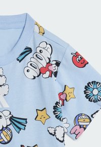 Camiseta de color azul claro con un escote acanalado que presenta varios estampados coloridos de estilo cartoon, incluyendo corazones, estrellas y nubes.