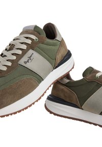 Zelene i smeđe tenisice s nubukom i mrežastim materijalima, s bijelim đonom i bež akcentima. Uključuju natikačić dizajn i detalj s logotipom.