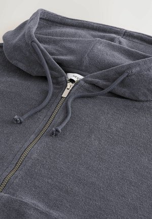 Tmavě šedá mikina na zip vyrobená z měkké tkaniny. Má podšívkovou kapuci, šňůrky na stažení a kovový zip s poutkem. Jednoduchý, texturovaný design.