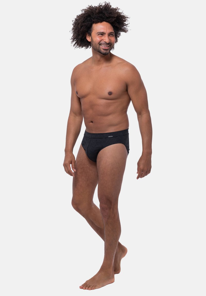 Zwarte gestreepte slips met een elastische tailleband, gemaakt van een zachte stof. De pasvorm is snug, en het ontwerp is eenvoudig en minimalistisch.