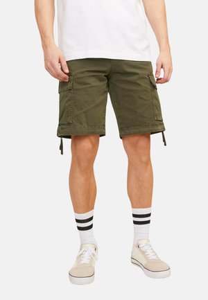 Shorts cargo verts olive avec deux poches latérales, ourlets à cordon, et longueur mi-cuisse, accompagnés de chaussettes blanches à rayures noires et de chaussures beiges.