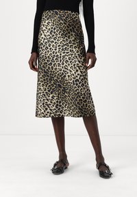 Leopard print midi skirt in a shiny fabric, featuring a slim fit and a smooth texture, paired with black flat shoes.
