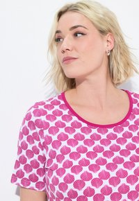 Camicia a maniche corte in cotone bianco con un motivo a conchiglie rosa, caratterizzata da un collo rotondo con un bordo rosa a contrasto.