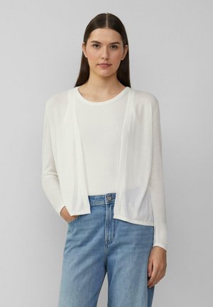 Witte lichtgewicht cardigan met een open voorkant, lange mouwen en een gestructureerde afwerking, gedragen over een witte top en gecombineerd met lichtblauwe jeans.