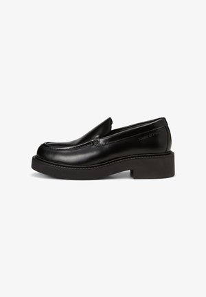 Chaussure noire en cuir avec un bout arrondi et une épaisse semelle plateforme noire. Présente des détails de couture subtils et un logo de marque sur le côté.
