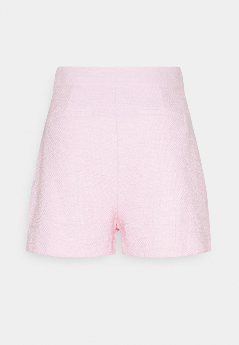 Short en tissu texturé rose clair avec taille haute et deux poches passepoilées à l'arrière sur un fond uni.