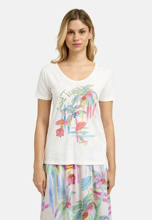 Woman wearing white scoop-neck t-shirt and skirt with colorful tropical palm tree, umbrella, and ice cream cart patterns.