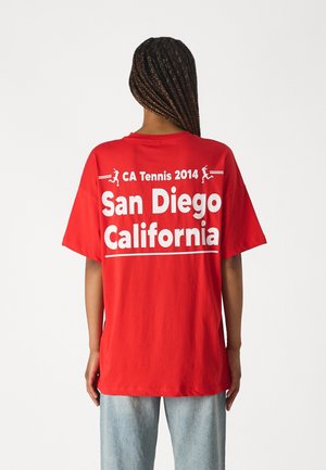Czerwona bawełniana koszulka z białym napisem na plecach: "CA Tennis 2014 San Diego California" oraz prostą grafiką przedstawiającą tenisistów.