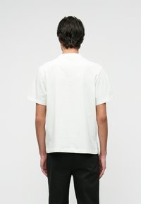 White cotton t-shirt with short sleeves, crew neck, relaxed fit, and subtle textured finish. Plain design with no visible patterns or accents.