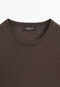Pull col rond marron foncé avec une étiquette noire visible cousue à l'intérieur de l'encolure portant l'inscription "Massimo Dutti".