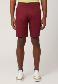 Bourgogne tygshorts med rak front, bälteshällor och sidofickor; parat med vita sneakers med beige detaljer.