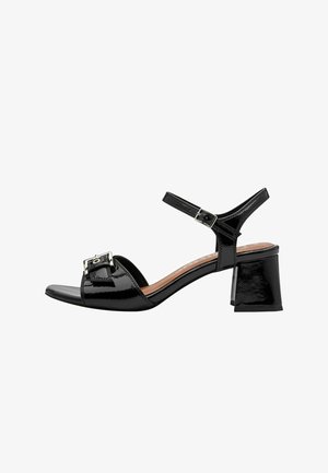 Sandale à talon en cuir verni noir avec orteil ouvert, bride à la cheville et un détail de boucle carrée sur le cou-de-pied. Dispose d'un talon bloc.