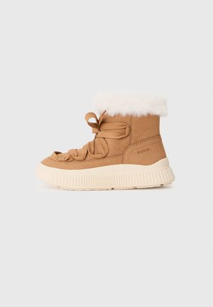 Botte de cheville en suède beige avec un revers en fausse fourrure blanche, des lacets en ruban et une semelle en caoutchouc épaisse couleur crème. Présente un design texturé et sportif.