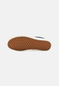 Sneaker talpája világos színű peremmel rendelkezik, textúrált barna gumiból készült alja pedig gyémántmintával van ellátva a tapadás érdekében.