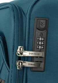 Teal bagage met gestructureerde stof, dubbele zilveren ritsen en een zwart cijferslot aan de zijkant.