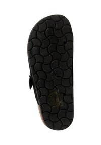 Semelle d'une sandale noire avec un motif de bande de roulement ondulé, taille marquée 36, et une petite étiquette avec des symboles et du texte près de la zone du talon.