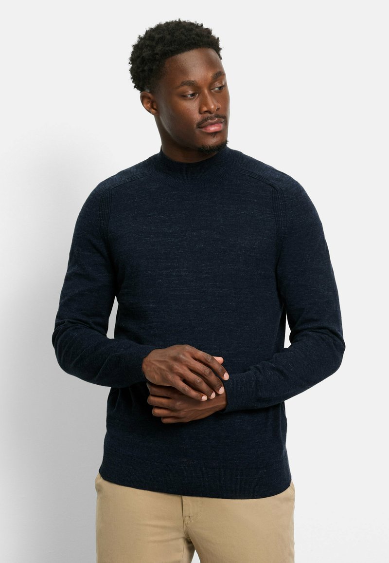 Marinefarbener Rundhals-Pullover aus strukturierter Strickware, mit gerippten Bündchen und Saum, kombiniert mit hellkhakifarbenen Hosen.