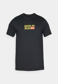 Black cotton t-shirt featuring a yellow "BERLIN" text and a red "RUN" text with a Nike swoosh logo in the center, short sleeves, and crew neck.