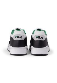 Zapatillas negras de cuero con suelas blancas, acentos verdes en el collar y detalles de malla. Logo de Fila en el talón. Diseño casual, estilo bajo.