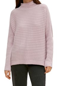 Lichtroze geribde trui met een hoge halslijn, losse pasvorm en lange mouwen, gemaakt van een zacht breimateriaal. Subtiele textuur met horizontale strepen.