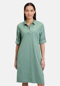 Hellgrünes Kleid mit Kragen, dreiviertel langen, hochgekrempelten Ärmel, lässiger Schnitt, aus glattem Stoff, knielang, mit minimaler Gestaltung.