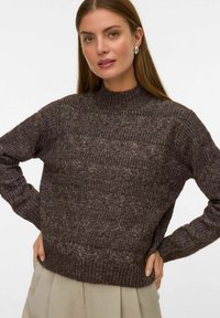 Maglione marrone lavorato a maglia con collo alto, caratterizzato da un motivo testurizzato e polsini e orlo a coste. Realizzato in un materiale morbido e caldo.