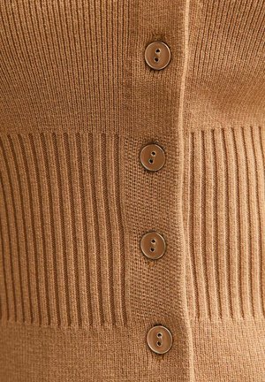 Close-up of brown knitted fabric with vertical ribbing and four round brown buttons in a vertical row.