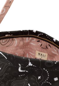 Sac à main noir à motifs avec un extérieur lisse orné de designs blancs et une doublure intérieure rose, fermeture éclair dorée et une étiquette portant l'inscription "NALI".