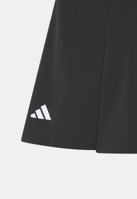 Svarta sportshorts i slätt tyg, med en vit logotyp med tre ränder på nedre vänstra sidan. Enkel design med rena linjer.