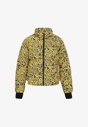 Keltainen leopardikuosiseltainen toppatakki, jossa on korkea kaulus, vetoketjusuljenta ja mustat neulotut hihansuut. Tikkaukset ja rohkeat eläinkuosat kauttaaltaan.