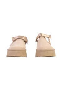 Paire de chaussures à plateforme en daim beige avec larges brides métalliques Velcro, vues de face sur fond blanc.