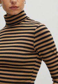 Langarmige turtleneck trui met horizontale strepen in bruin en zwart, zachte textuur, aansluitend ontwerp en hoge kraag.