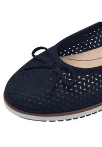 Navy perforated leather shoe with a bow accent, featuring a round toe, cushioned insole, and a white rubber sole with black grooves.