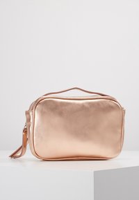 Metallisk roséguld kosmetikväska med en slät yta, rektangulär form, dragkedjestängning och ett kort handtag för enkel transport.
