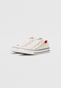 Off-white vászon tornacipő, kontrasztos fekete csíkokkal. Piros részletekkel és hímezett gyümölcsmotívumokkal rendelkezik. Gumitalp, klasszikus fűzős stílus.
