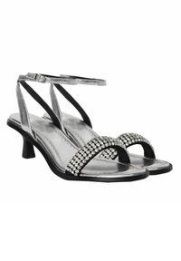 Sandalias plateadas con tiras y tacón bajo, con una base negra y adornadas con una fila de strass transparentes en la zona del dedo del pie.