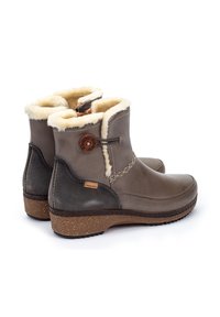 Bottines en cuir marron avec doublure en fausse fourrure, couture décorative et semelle en liège. Comprend une étiquette de logo et une fermeture éclair sur le côté pour un accès facile.