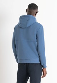 Felpa blu realizzata in tessuto morbido, con cappuccio regolabile tramite cordoncino, polsini a coste e una vestibilità morbida, caratterizzata da una cucitura orizzontale sulla schiena.