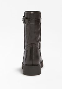 Botte de cheville en cuir noir avec un haut tige, accent de boucle et détail texturé. Dotée d'une solide semelle en caoutchouc plate et de coutures visibles.