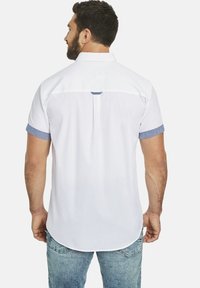 Weißes Kurzarmhemd mit denimblauen Akzenten an den Ärmeln und Rückendetails; verfügt über einen abgerundeten Saum und eine Rückenfalte für bequeme Bewegungsfreiheit.