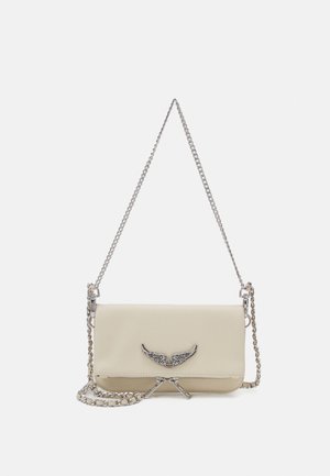 Bolso de piel color crema con una correa de cadena plateada. Presenta un acento metálico en forma de ala en la parte frontal y un acabado de textura suave.