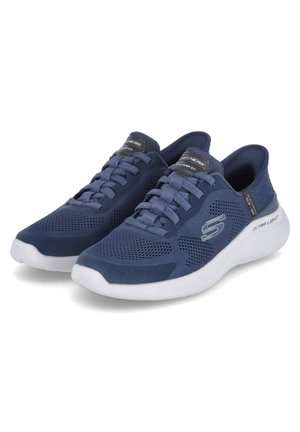 Baskets de sport bleu marine avec un design en mesh, lacets plats, col rembourré et semelle légère blanche. Présente un détail de logo sur le côté.