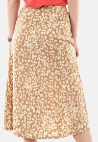 Una falda midi beige con un estampado de leopardo crema. Fabricada con un tejido suave, tiene una textura lisa y una forma acampanada.