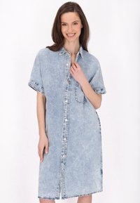 Denim-mekko vaaleansinisellä värillä, jossa on lyhyet hihat, nappikiinnitys edessä ja sivutaskut. Ominaisuuksiin kuuluu rento istuvuus ja viimeistelty helma, jossa on purjehdusreunat.