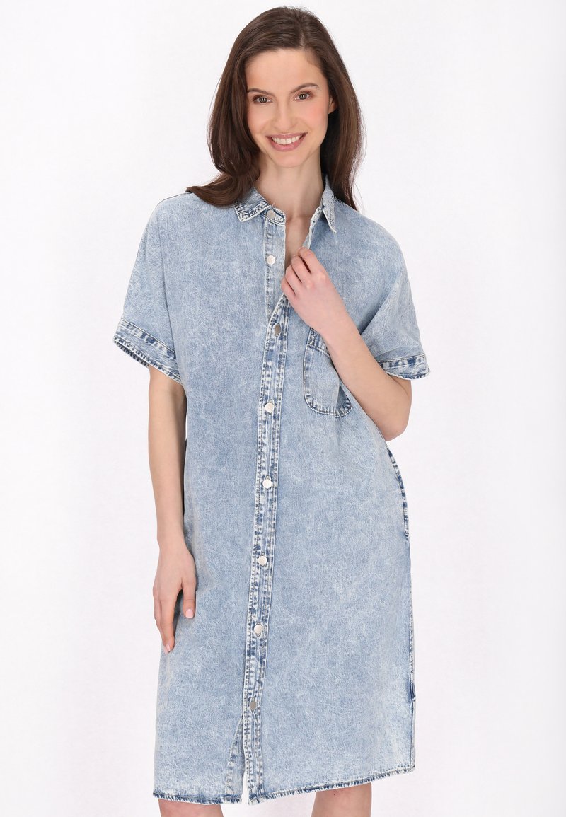 Denim-mekko vaaleansinisellä värillä, jossa on lyhyet hihat, nappikiinnitys edessä ja sivutaskut. Ominaisuuksiin kuuluu rento istuvuus ja viimeistelty helma, jossa on purjehdusreunat.